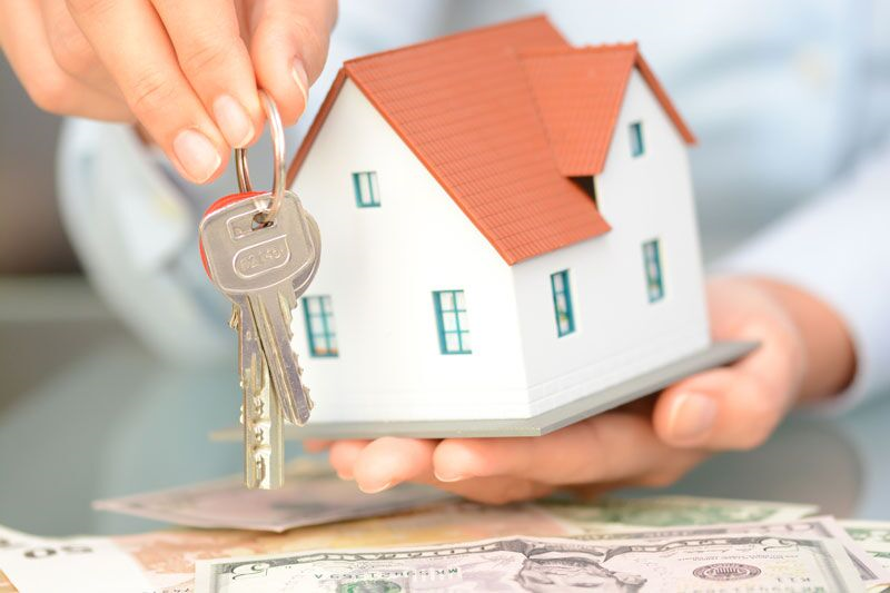 man holding a model of a home and a set of keys, insurance factors that home buyers should consider